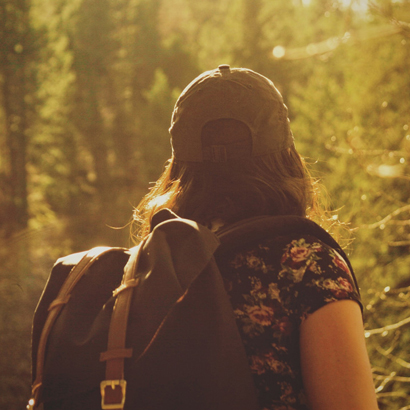 Woman Hiking In Sunlit Forest.