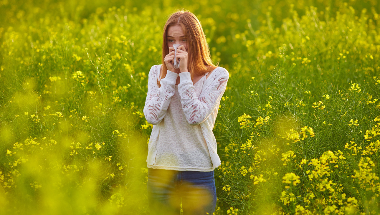 Woman Blowing Her Nose Standing In A Field Of Yellow Flowers.