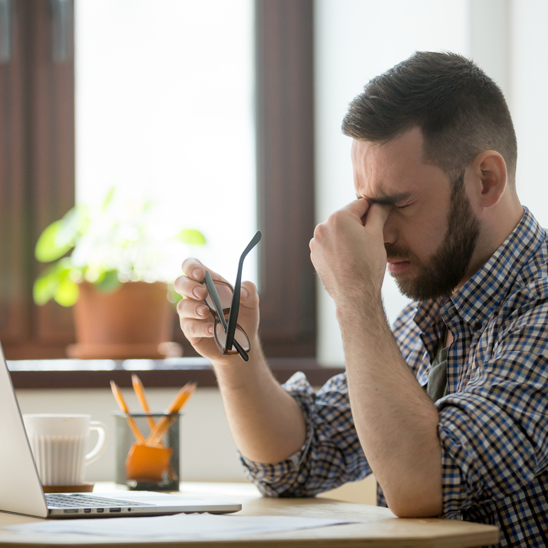 Man Squeezing Tired Eyes In Front Of Laptop.